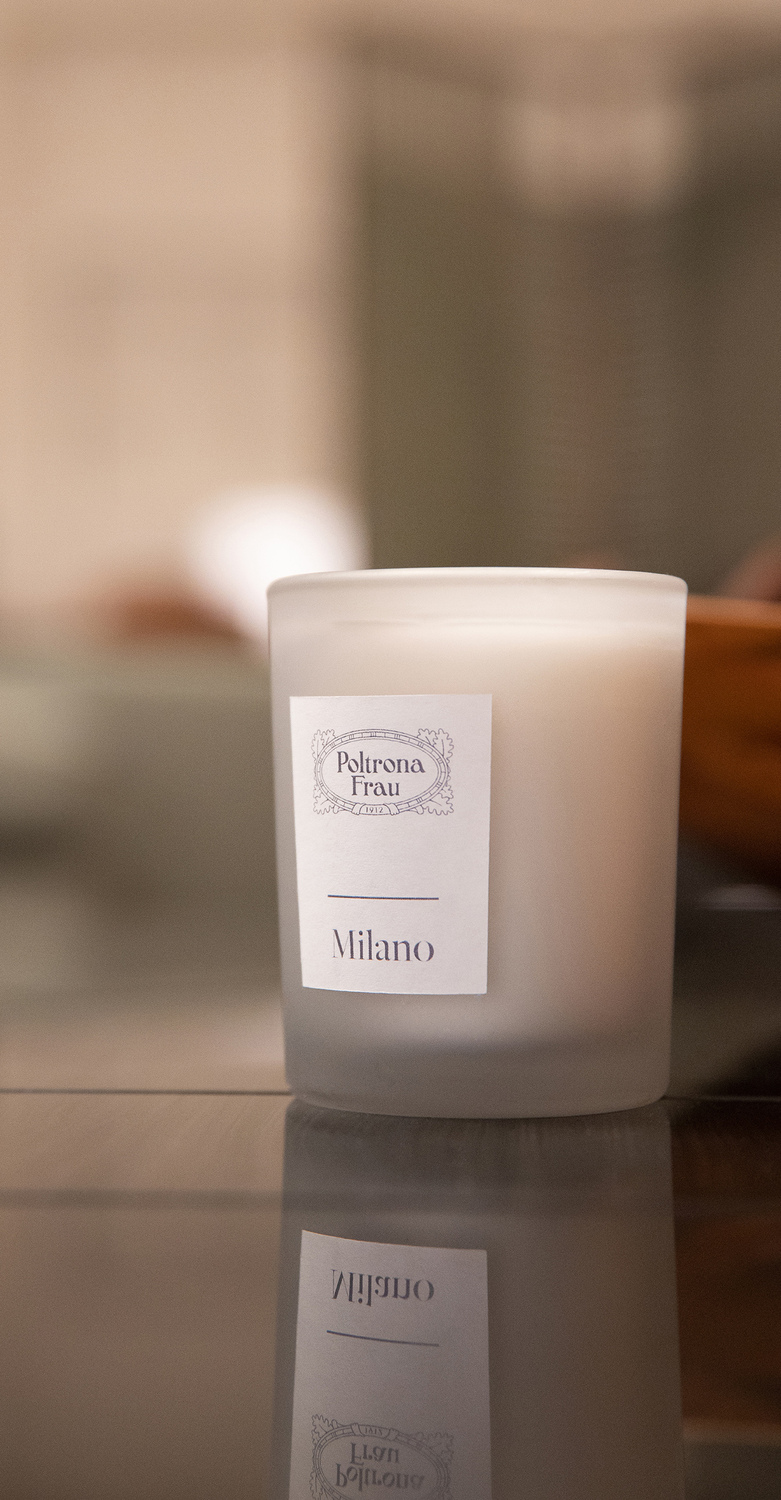 Milano | Candela Milano Candle Poltrona Frau, vetro satinato grigio con etichetta bianca, fragranza legnoso orientale con note di pelle nera, tonka e violetta, omaggio all’eleganza milanese
